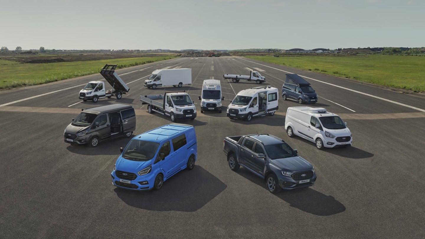 Verschiedene Ford Transit, die auf einem offenen Gelände ausgestellt sind. Die Fahrzeuge umfassen unterschiedliche Modelle, die die Vielseitigkeit und Robustheit der Ford Transporter für den gewerblichen Einsatz, wie Lieferungen und Handwerksarbeiten, zeigen.